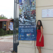 artist Brooke Harker with exhibition banner in Italy